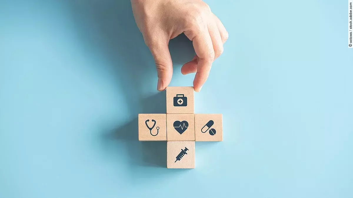 Kreuz aus Holzwürfeln mit Symbolen der Gesundheitsversorgung