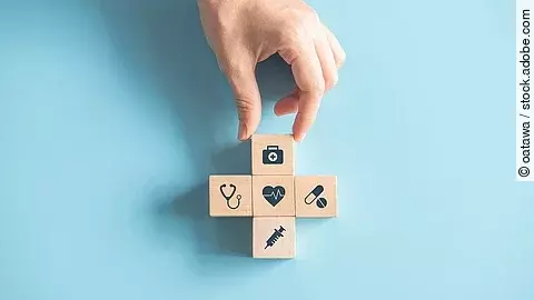 Kreuz aus Holzwürfeln mit Symbolen der Gesundheitsversorgung