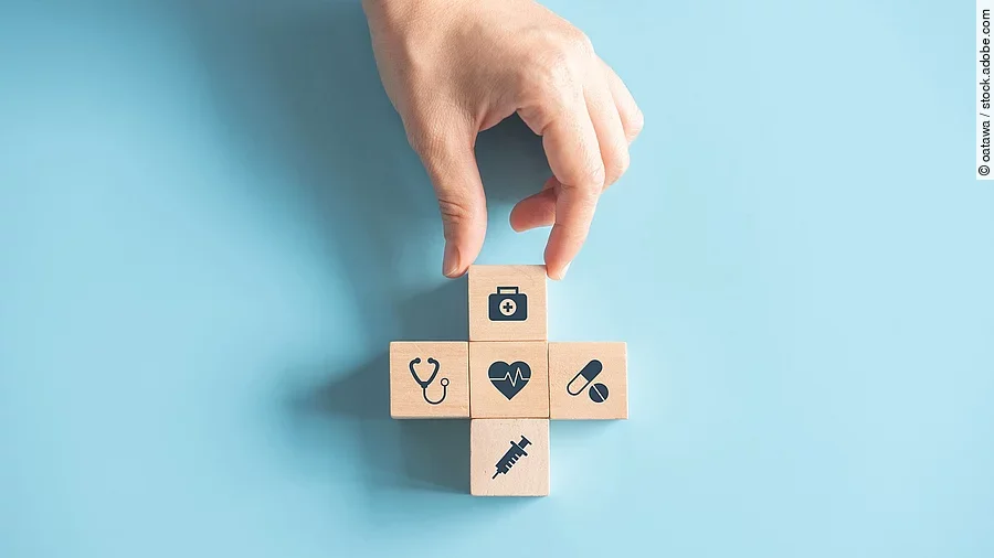 Kreuz aus Holzwürfeln mit Symbolen der Gesundheitsversorgung