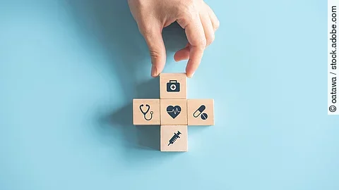 Kreuz aus Holzwürfeln mit Symbolen der Gesundheitsversorgung