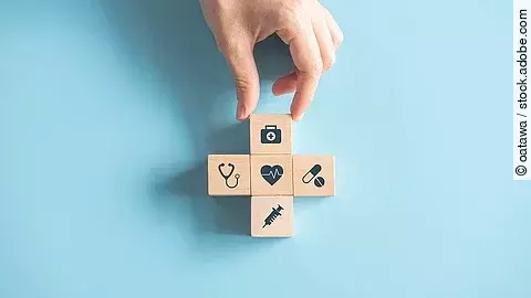 Kreuz aus Holzwürfeln mit Symbolen der Gesundheitsversorgung