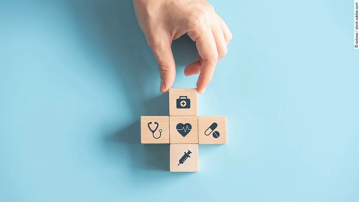 Kreuz aus Holzwürfeln mit Symbolen der Gesundheitsversorgung