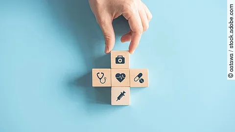 Kreuz aus Holzwürfeln mit Symbolen der Gesundheitsversorgung