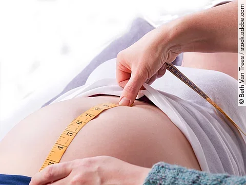 Zu sehen sind die Hände einer Hebamme, die den Bauch einer schwangeren Frau abmisst.