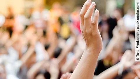 Hochgehobene Hand vor einer Gruppe von Menschen
