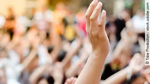 Hochgehobene Hand vor einer Gruppe von Menschen