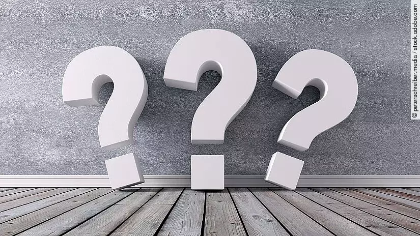 Drei Fragezeichen vor einer grauen Wand 