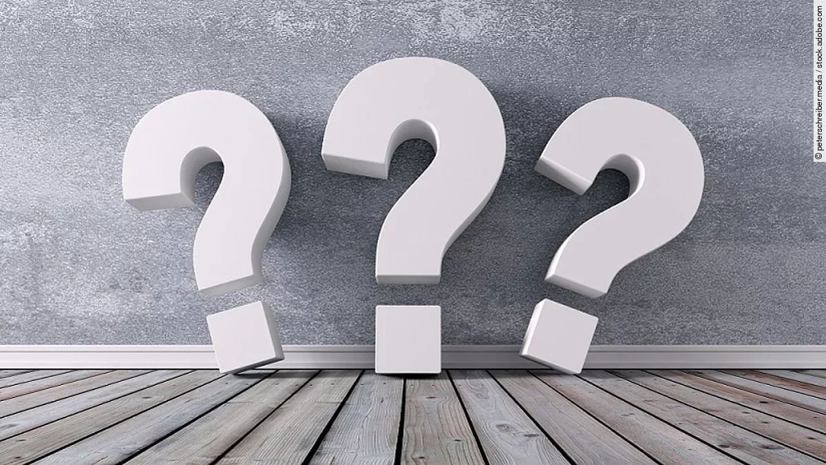 Drei Fragezeichen vor einer grauen Wand 