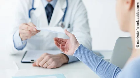 Ein Arzt überreicht einer Patientin ein Dokument.