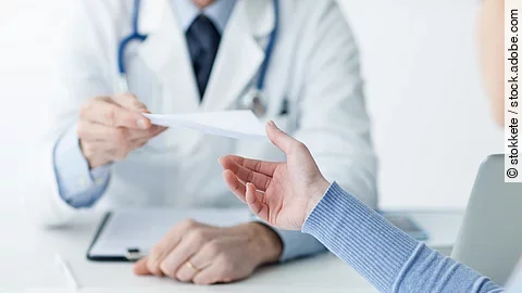 Ein Arzt überreicht einer Patientin ein Dokument.