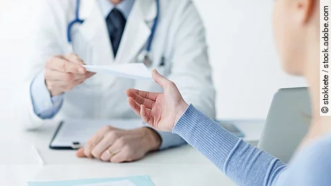 Ein Arzt überreicht einer Patientin ein Dokument.