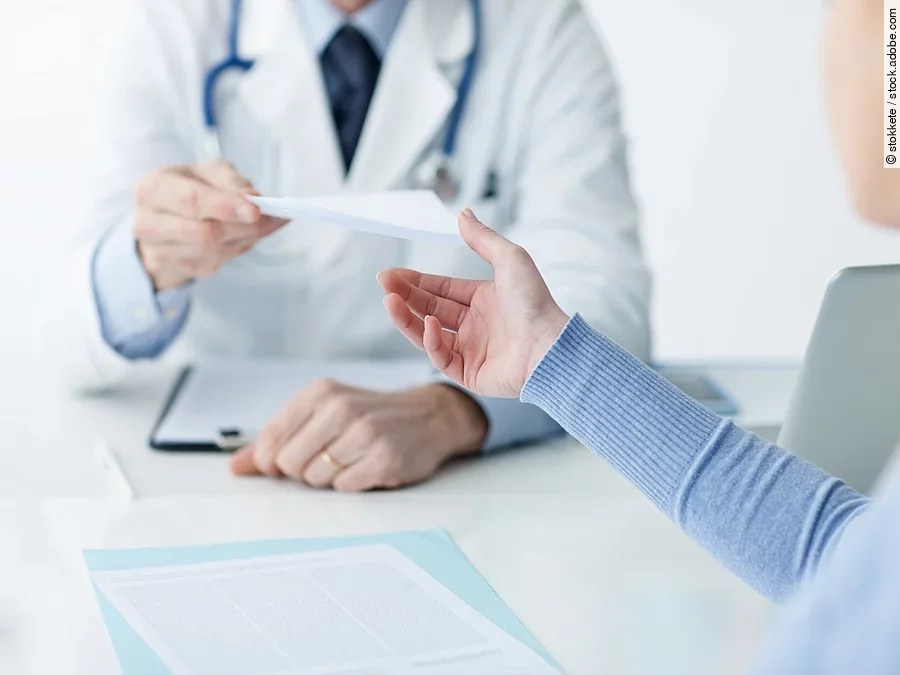Arzt mit Patientin Ein Arzt überreicht einer Patientin ein Dokument.