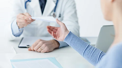 Ein Arzt überreicht einer Patientin ein Dokument.