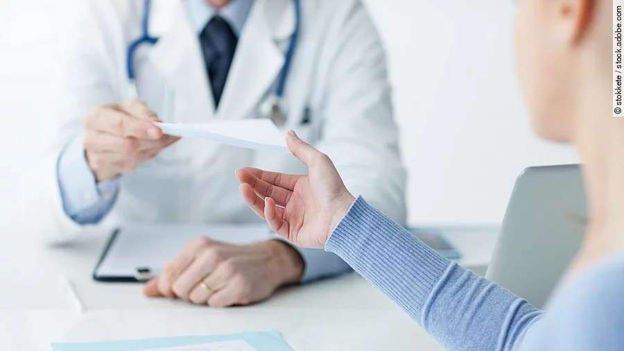 Arzt mit Patientin Ein Arzt überreicht einer Patientin ein Dokument.