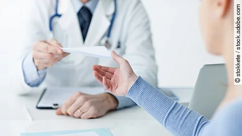 Ein Arzt überreicht einer Patientin ein Dokument.
