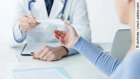 Ein Arzt überreicht einer Patientin ein Dokument.