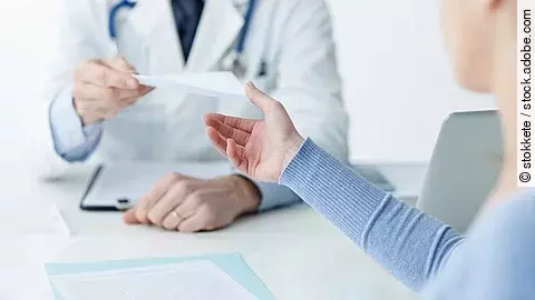 Ein Arzt überreicht einer Patientin ein Dokument.