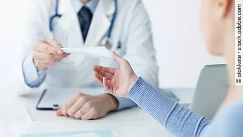 Ein Arzt überreicht einer Patientin ein Dokument.