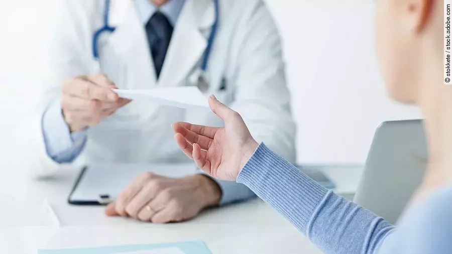 Ein Arzt überreicht einer Patientin ein Dokument.
