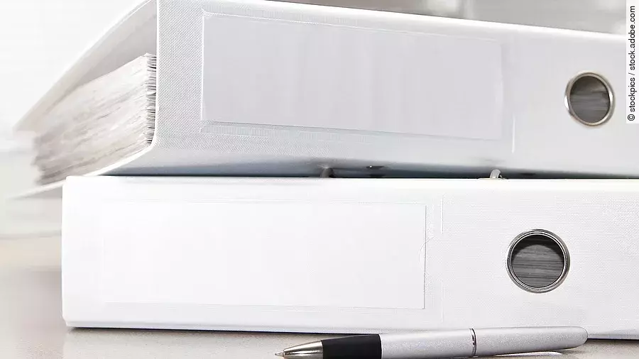 Aktenordner Zwei weiße Aktenordner liegen übereinander. Davor liegt ein silberner Kugelschreiber.