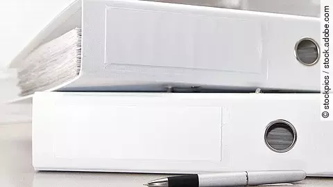 Aktenordner Zwei weiße Aktenordner liegen übereinander. Davor liegt ein silberner Kugelschreiber.