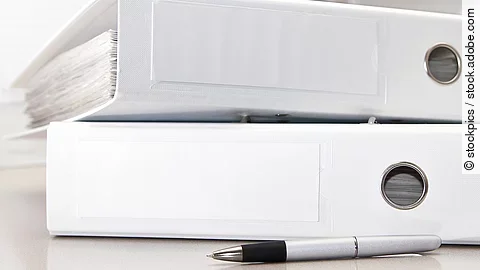 Zwei weiße Aktenordner liegen übereinander. Davor liegt ein silberner Kugelschreiber.