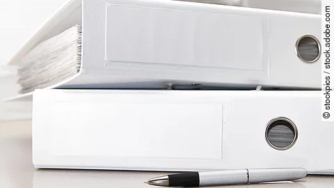 Zwei weiße Aktenordner liegen übereinander. Davor liegt ein silberner Kugelschreiber.