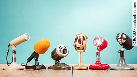 Mehrere Mikrofone stehen vor einem türkisen Hintergrund.