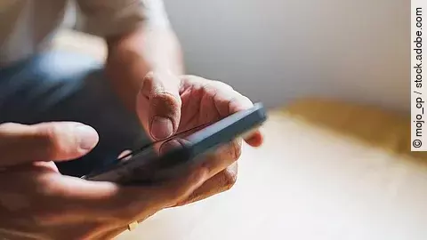 Hände tippen auf ein Handy