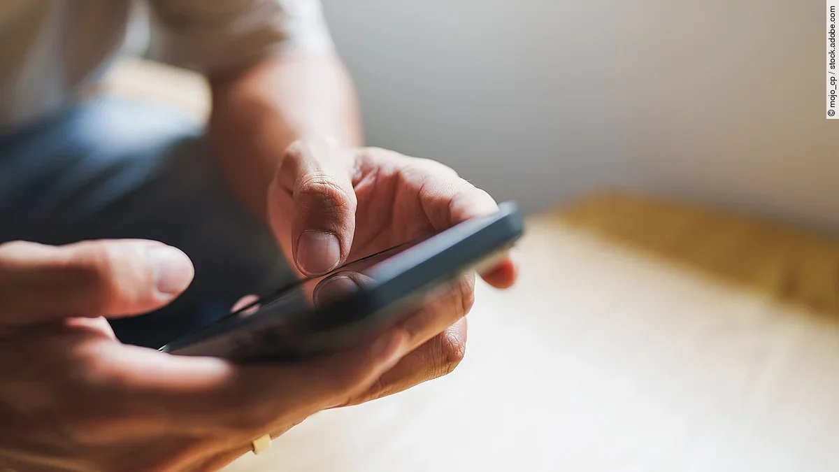 Hände tippen auf ein Handy