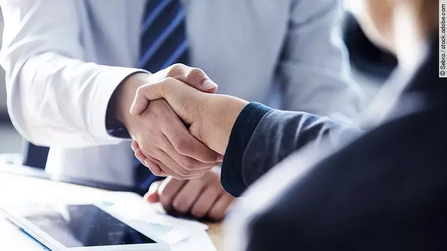 Händeschütteln zweier sich gegenübersitzenden Personen