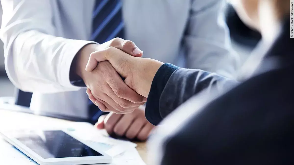 Händeschütteln zweier sich gegenübersitzenden Personen