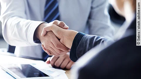 Händeschütteln zweier sich gegenübersitzenden Personen