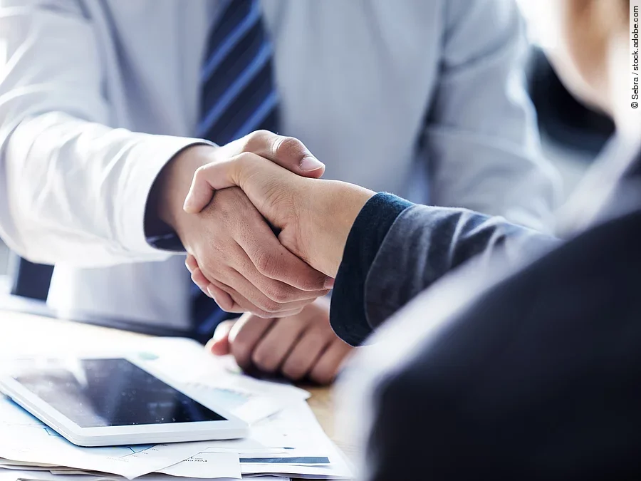 Händeschütteln zweier sich gegenübersitzenden Personen