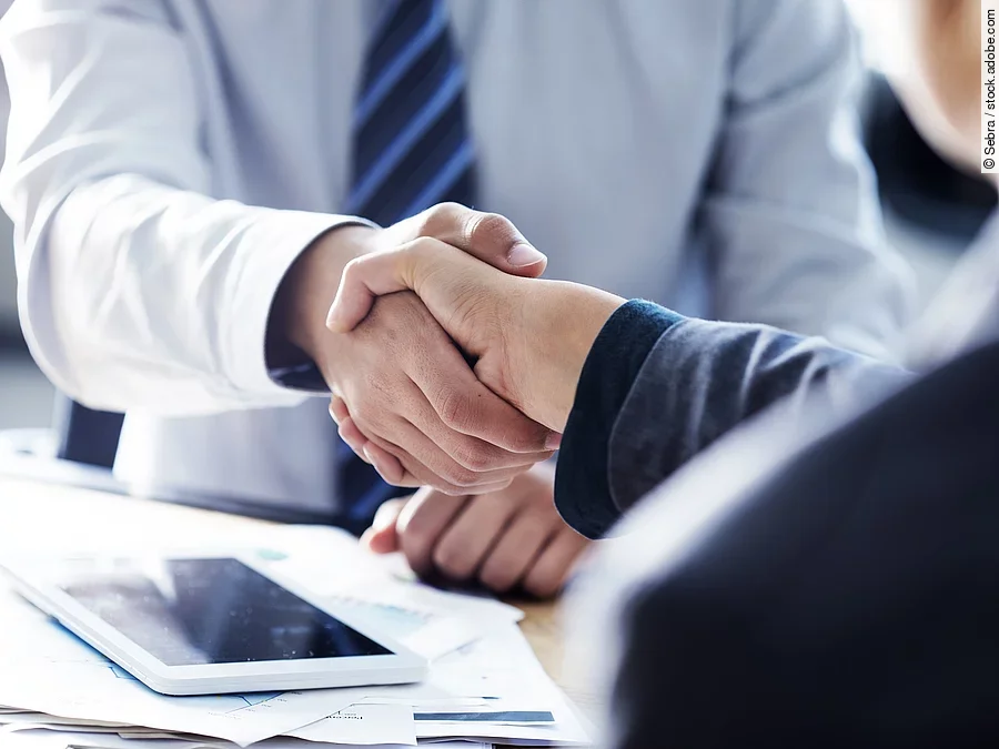 Händeschütteln zweier sich gegenübersitzenden Personen