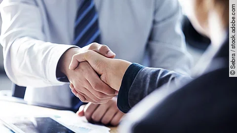 Händeschütteln zweier sich gegenübersitzenden Personen