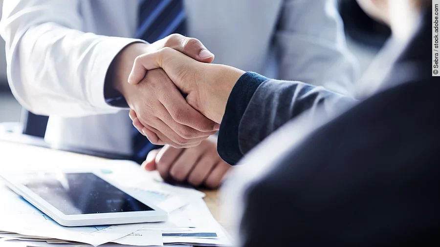 Händeschütteln zweier sich gegenübersitzenden Personen
