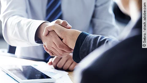 Händeschütteln zweier sich gegenübersitzenden Personen