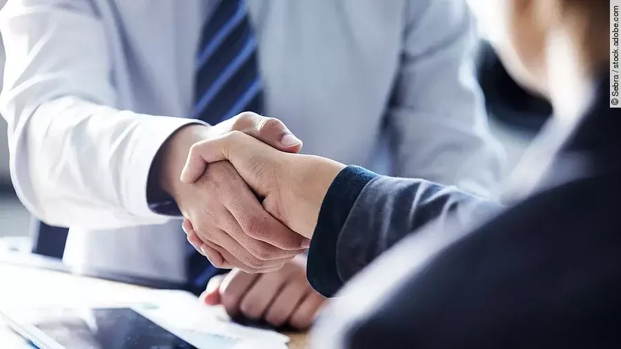 Händeschütteln zweier sich gegenübersitzenden Personen