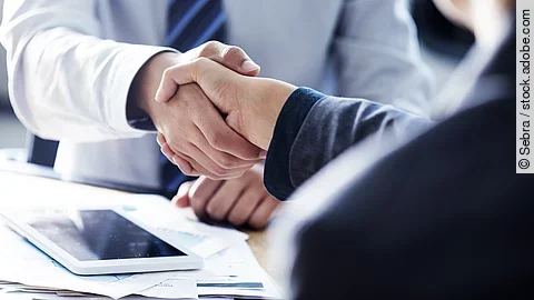 Händeschütteln zweier sich gegenübersitzenden Personen