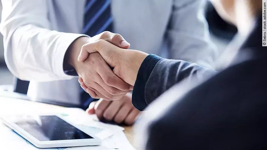 Händeschütteln zweier sich gegenübersitzenden Personen