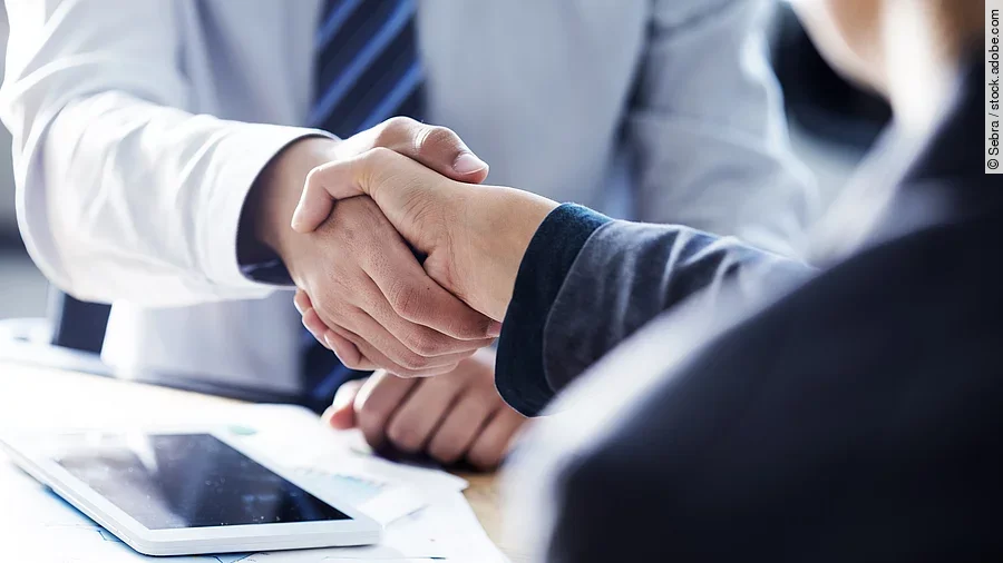 Händeschütteln zweier sich gegenübersitzenden Personen
