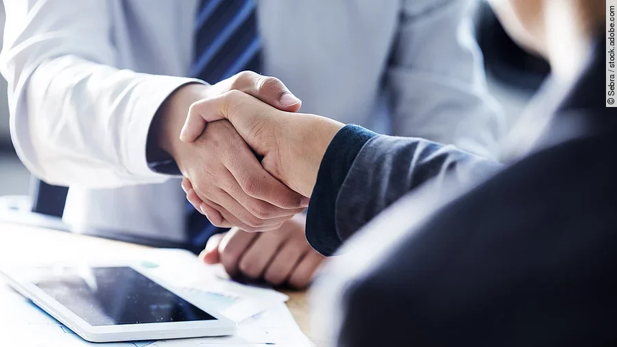 Händeschütteln zweier sich gegenübersitzenden Personen