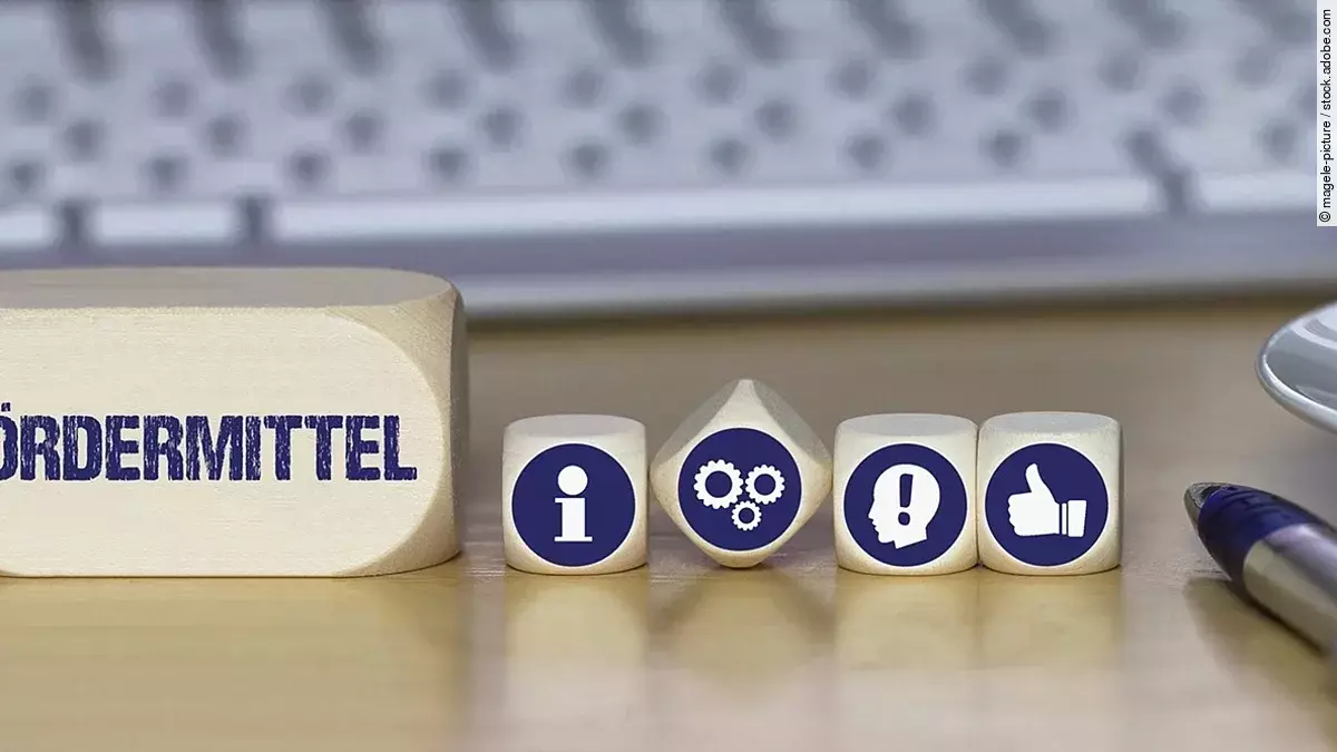 Fördermittel Ein Holzklotz mit der Aufschrift Fördermittel. Daneben liegen Würfel mit den Symbolen i (für Information), Zahnrädchen, ein Kopf mit einem Ausrufezeichen und ein Daumen-hoch.