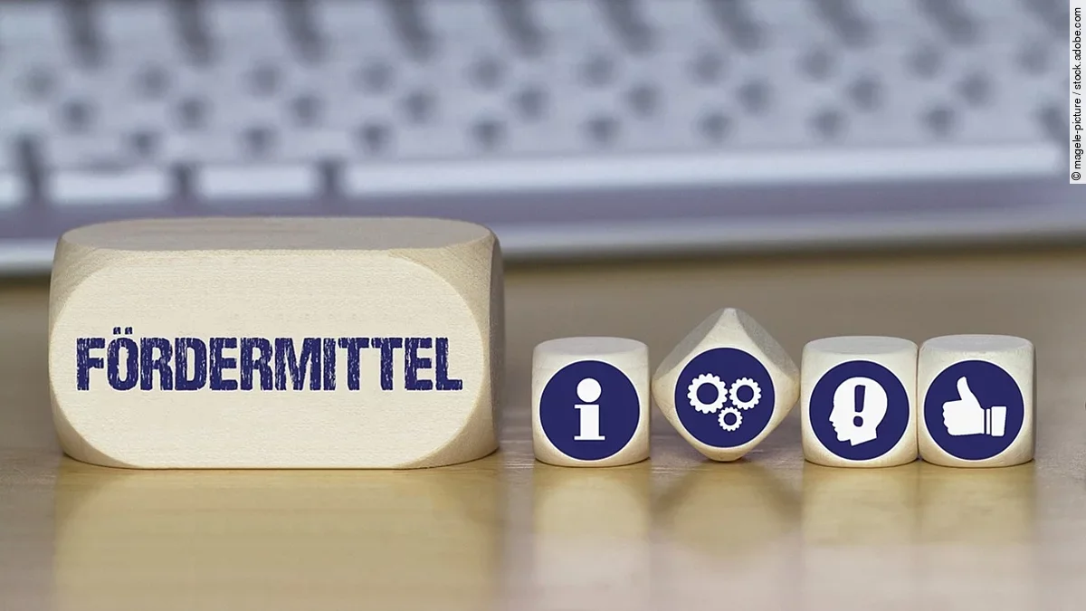 Fördermittel Ein Holzklotz mit der Aufschrift Fördermittel. Daneben liegen Würfel mit den Symbolen i (für Information), Zahnrädchen, ein Kopf mit einem Ausrufezeichen und ein Daumen-hoch.