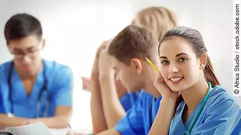 Ausbildung Eine Gruppe an (Pflege-)Auszubildenden sitzt nebeneinander am Tisch.