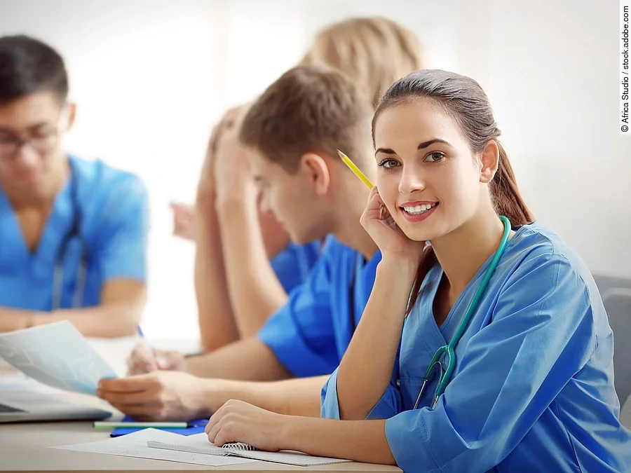 Ausbildung Eine Gruppe an (Pflege-)Auszubildenden sitzt nebeneinander am Tisch.