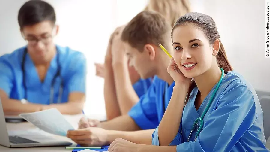 Ausbildung Eine Gruppe an (Pflege-)Auszubildenden sitzt nebeneinander am Tisch.