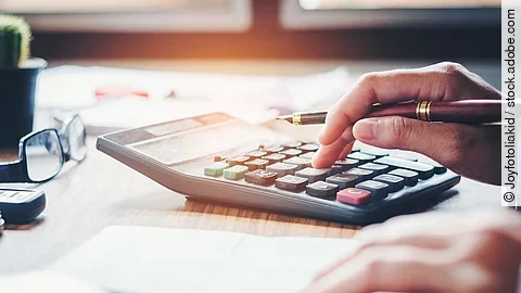 Ein Mann tippt etwas in einen Taschenrechner. Vor ihm liegt ein Blatt Papier.