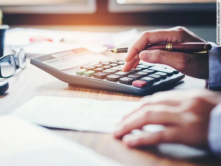 Rechnung Ein Mann tippt etwas in einen Taschenrechner. Vor ihm liegt ein Blatt Papier.